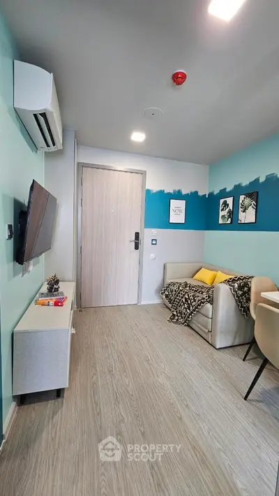 Modern living room with stylish decor, featuring a cozy sofa, wall-mounted TV, and air conditioning unit.