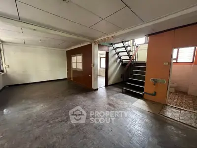 Spacious interior with staircase and large windows, ideal for renovation or creative transformation.