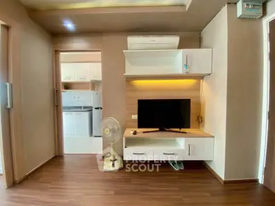 Modern living room with wooden flooring, wall-mounted TV, and sleek storage units.
