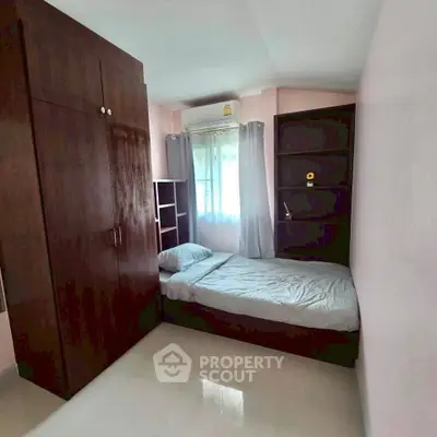 Cozy bedroom with natural light, featuring a bed, wardrobe, and shelves, perfect for comfortable living.