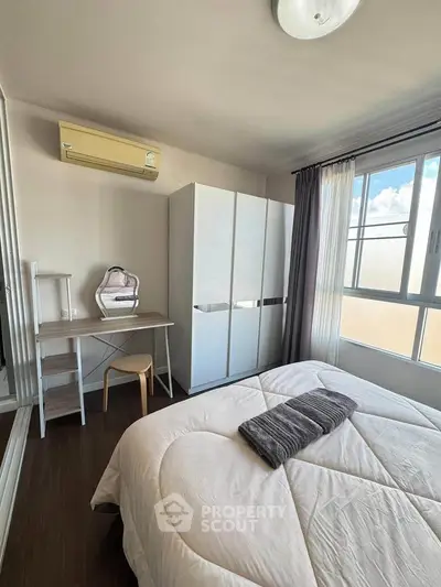 Cozy bedroom with modern furniture and large window offering natural light.