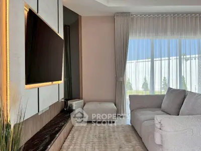 Modern living room with large TV and cozy sofa, featuring elegant curtains and natural light.