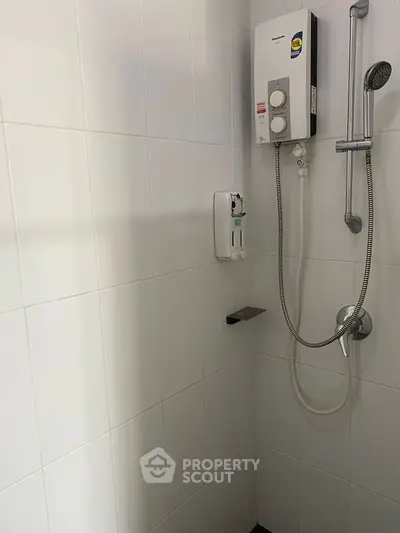 Modern bathroom with sleek shower and water heater in a minimalist design.