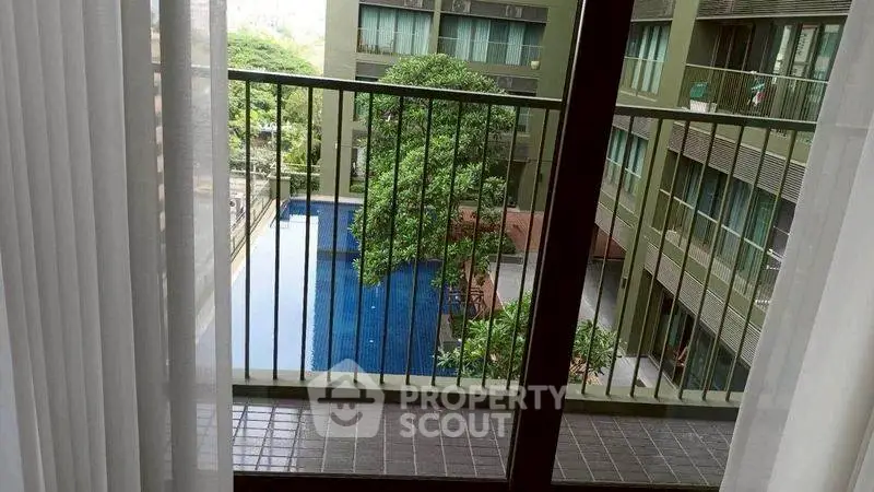 Stunning pool view from a modern apartment balcony with lush greenery.