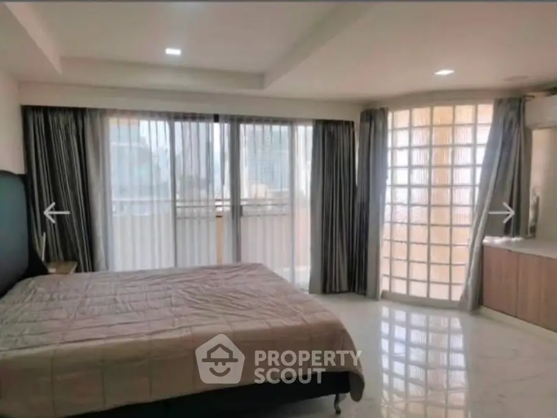 Spacious bedroom with large windows and modern decor in a luxury apartment.