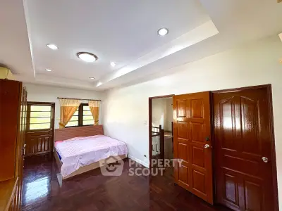 Spacious bedroom with wooden flooring and ample natural light