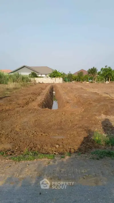 Expansive plot of land with potential for development, featuring clear skies and surrounding greenery.