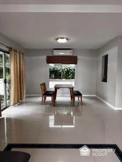 Spacious dining area with large windows and modern furniture in a bright home.