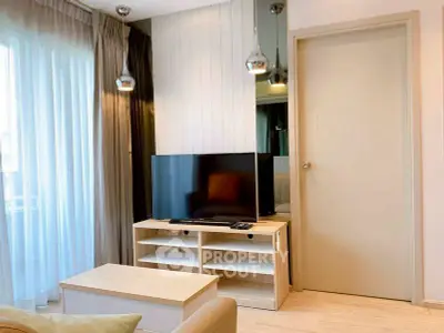 Modern living room with TV, stylish lighting, and natural light from large window.