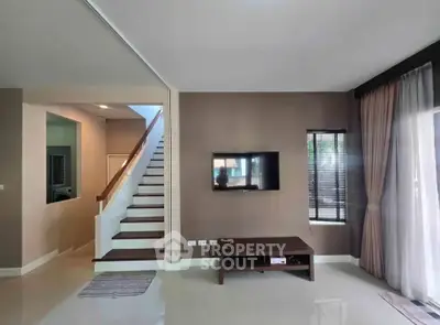 Modern living room with staircase and wall-mounted TV in a stylish home interior.