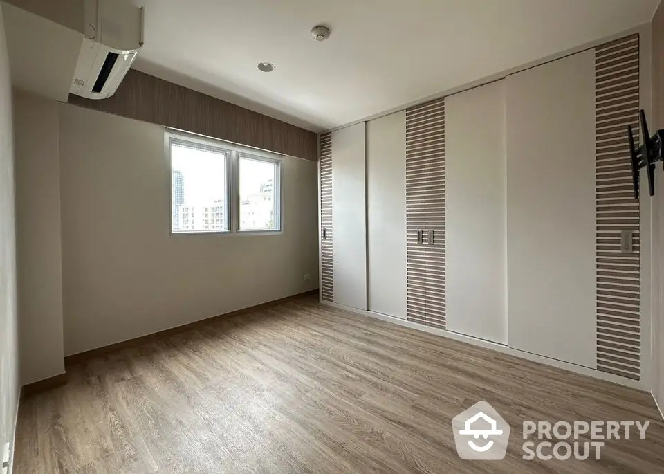 Spacious empty bedroom with built-in wardrobe and air conditioning