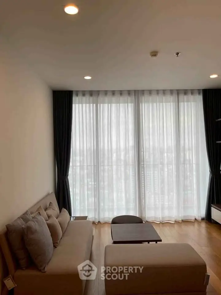 Spacious living room with large windows and modern furniture in a high-rise apartment.