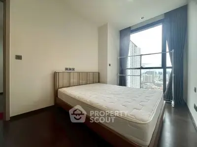 Modern bedroom with large window offering city view and natural light.