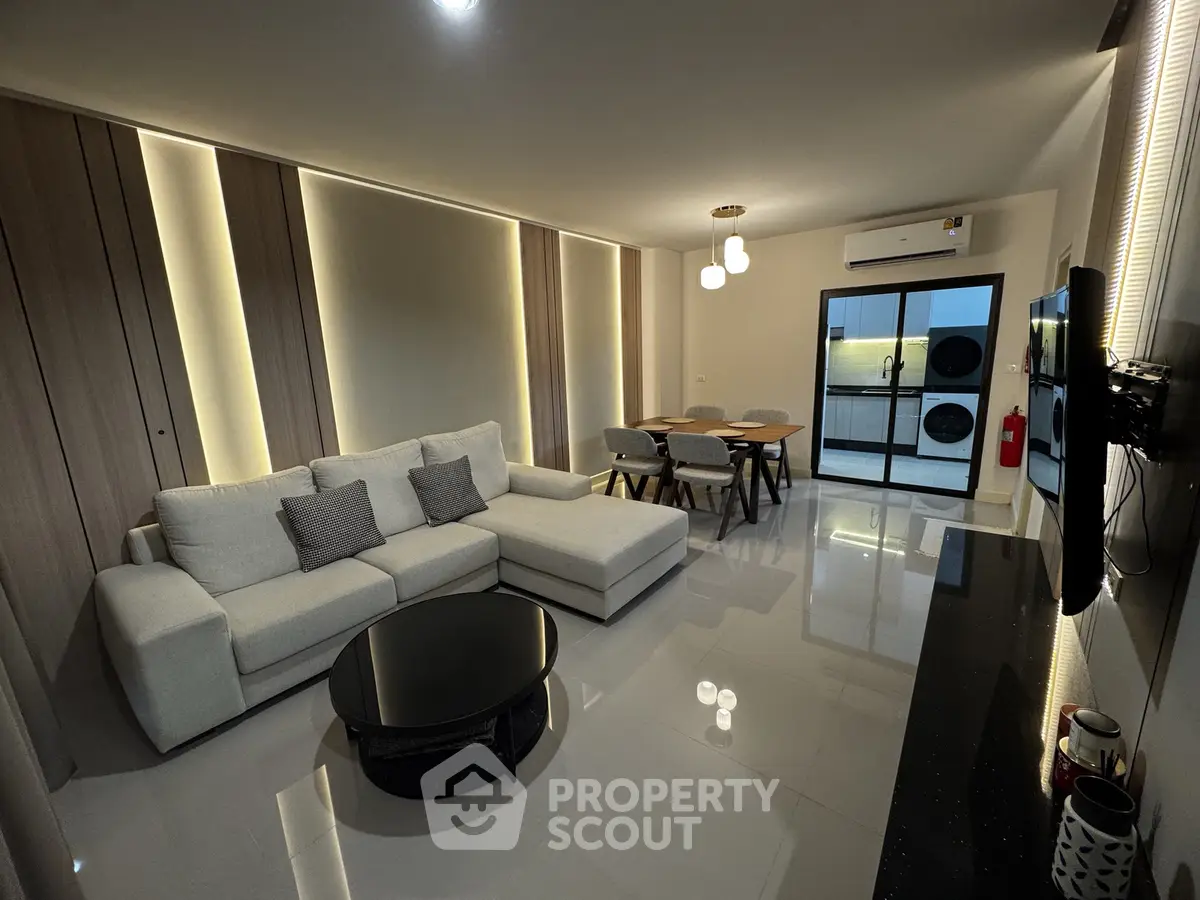 Modern living room with sleek design, featuring a spacious sectional sofa, dining area, and stylish lighting.
