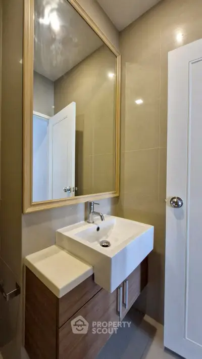 Modern bathroom with sleek sink and large mirror in elegant design.