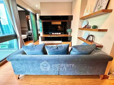 Modern living room with stylish sofa and entertainment center, featuring large windows and elegant decor.