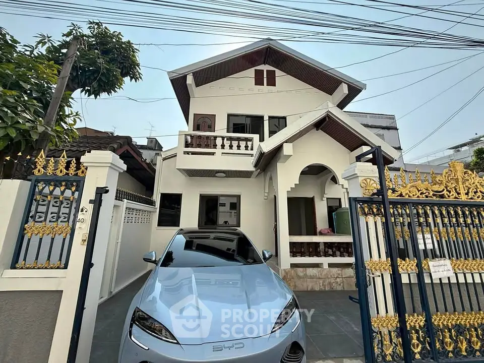 Charming two-story house with elegant gate and modern car in driveway