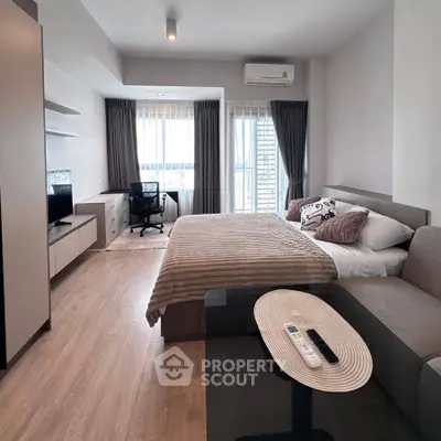 Modern studio apartment with cozy bed, study area, and natural light.