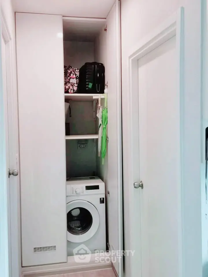 Compact laundry area with washing machine and storage shelves in modern home.