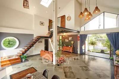 Stunning open-plan living room with high ceilings and modern decor, featuring unique staircase and large windows.