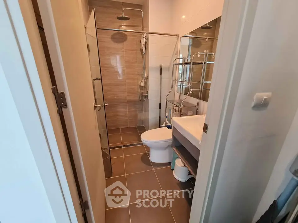 Modern bathroom with glass shower and sleek fixtures in contemporary apartment.