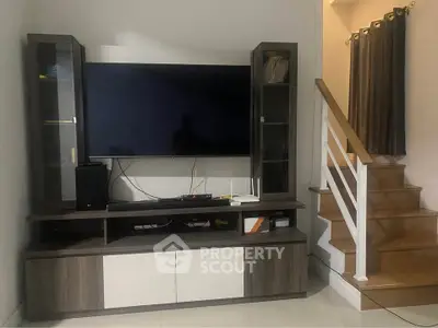 Modern living room with sleek TV unit and wooden staircase