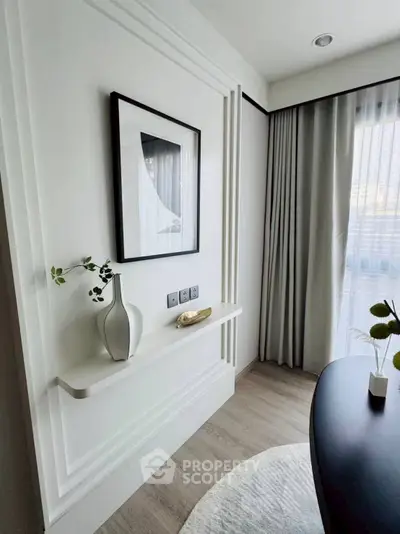 Elegant modern interior with stylish decor and natural light, featuring a framed artwork and sleek furniture.