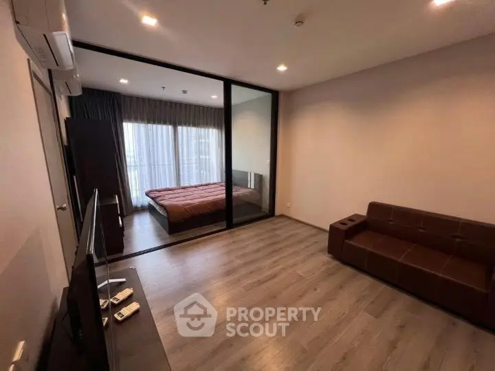 Modern apartment with open living room and bedroom design, featuring sleek wooden flooring.