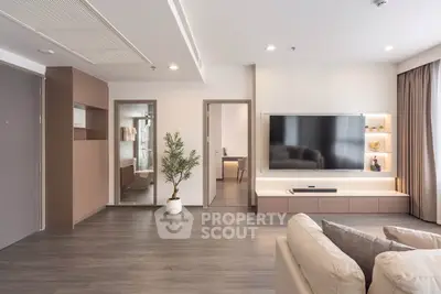 Modern living room with sleek TV setup and cozy seating area, featuring elegant decor and ample natural light.