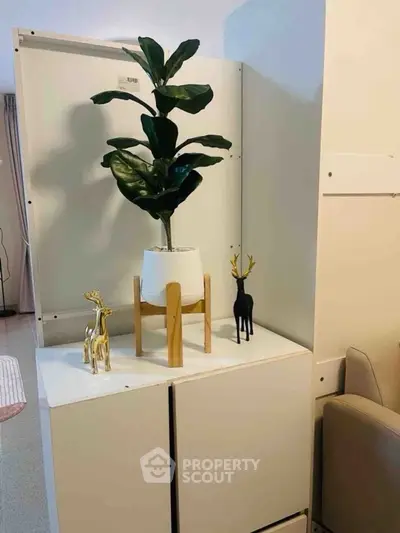 Modern interior decor with stylish plant and deer figurines on white cabinet.