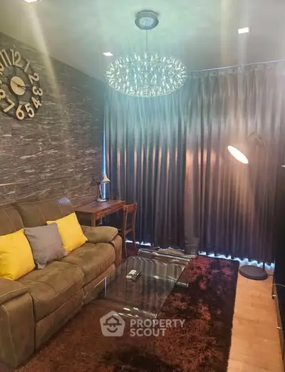 Cozy living room with modern decor, plush sofa, stylish chandelier, and elegant curtains.