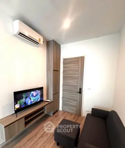 Modern living room with sleek furniture and wall-mounted TV, featuring air conditioning and stylish wood accents.