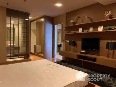 Elegant bedroom with modern furnishings, ambient lighting, and a cozy atmosphere, featuring a large bed, built-in shelves, and a flat-screen TV.