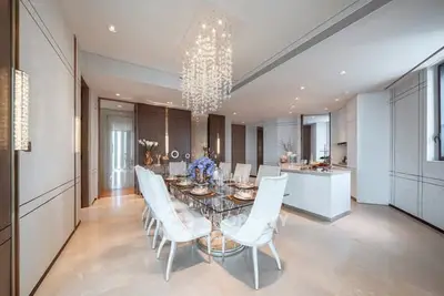 Luxurious dining area with elegant chandelier and modern kitchen in open layout.