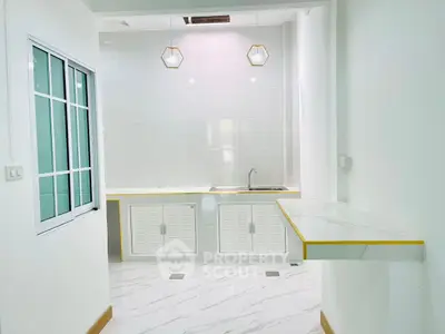 Modern kitchen with sleek white cabinets and marble countertops in a bright interior.