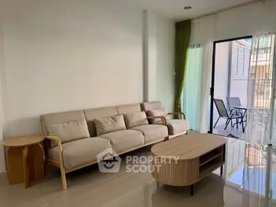 Modern living room with elegant beige sofa and stylish coffee table, opening to a sunlit balcony.