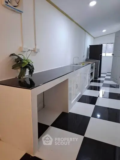 Modern kitchen with sleek black countertop and checkered floor tiles