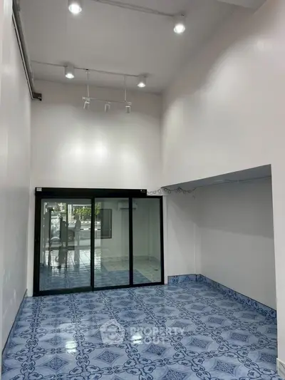 Spacious commercial space with high ceilings and elegant blue tile flooring, ideal for retail or office use.