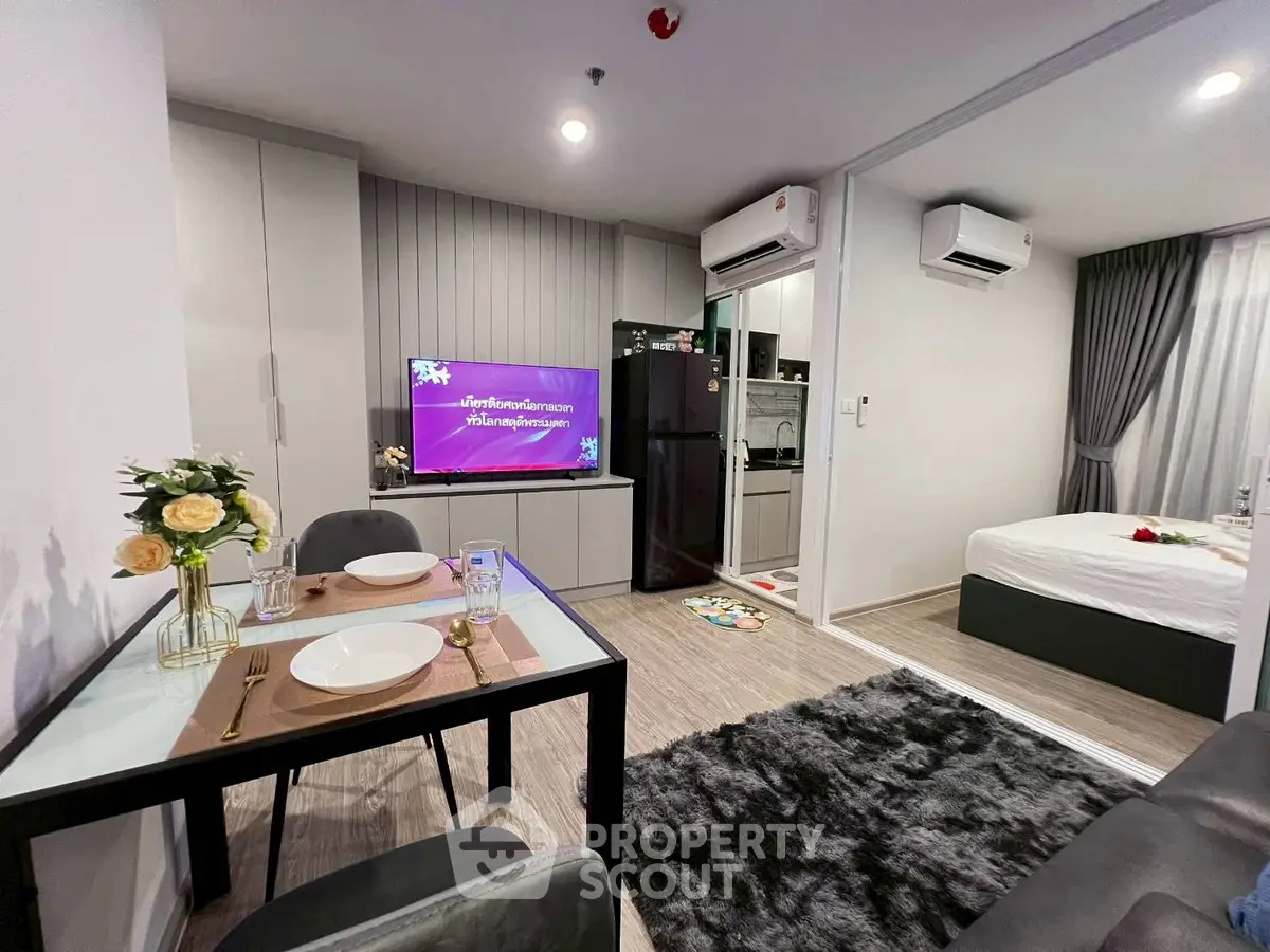 Modern open-plan living room with dining area and bedroom, featuring sleek decor and cozy ambiance.