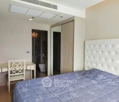 Spacious bedroom with elegant decor and ensuite bathroom in modern apartment.