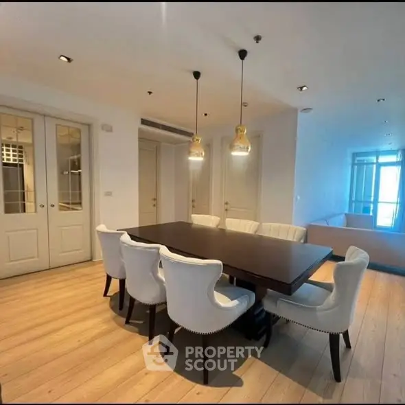 Elegant dining area with modern lighting and stylish seating in a spacious apartment.