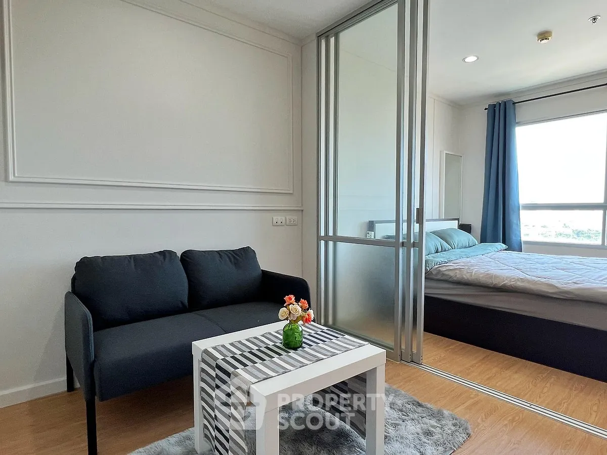 Modern apartment with cozy living room and bedroom separated by glass sliding doors, featuring stylish decor.