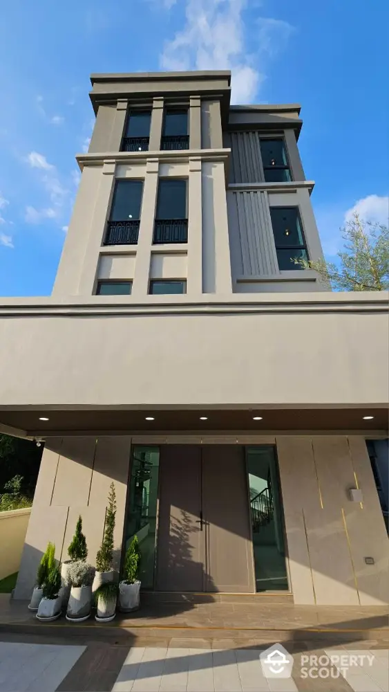 Modern multi-story building with elegant facade and clear blue sky backdrop.