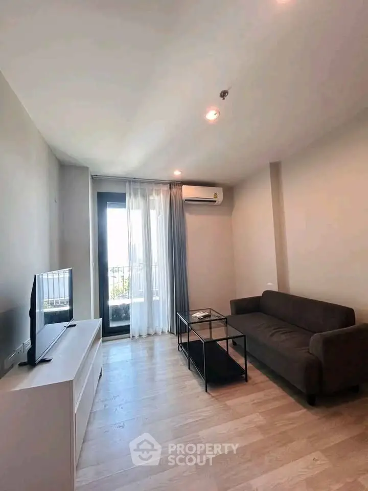 Modern living room with sleek furniture and natural light, featuring a cozy sofa and a large window view.