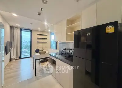 Modern open-layout kitchen with sleek black fridge and city view from living area.