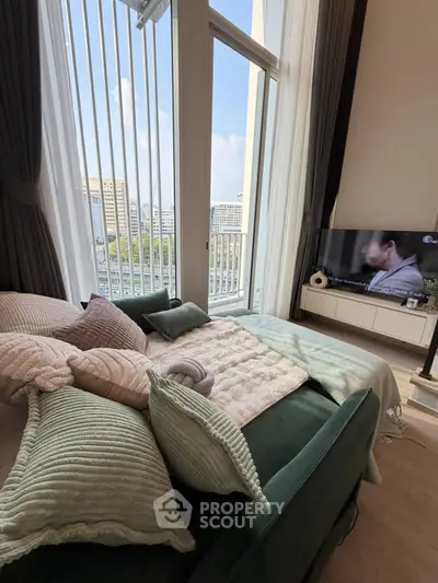 Luxurious bedroom with floor-to-ceiling windows and city view, featuring a cozy bed and modern TV setup.