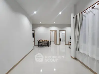 Spacious modern living area with elegant dining setup and large windows.