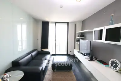Modern living room with sleek black furniture and large window balcony view.