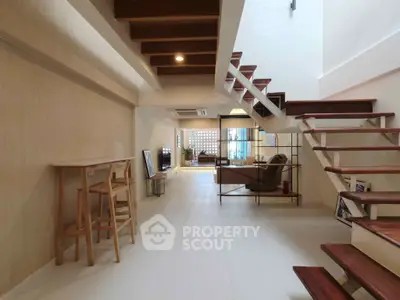 Modern open-plan living area with stylish staircase and wooden accents