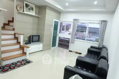 Modern living room with sleek black sofas and stylish staircase